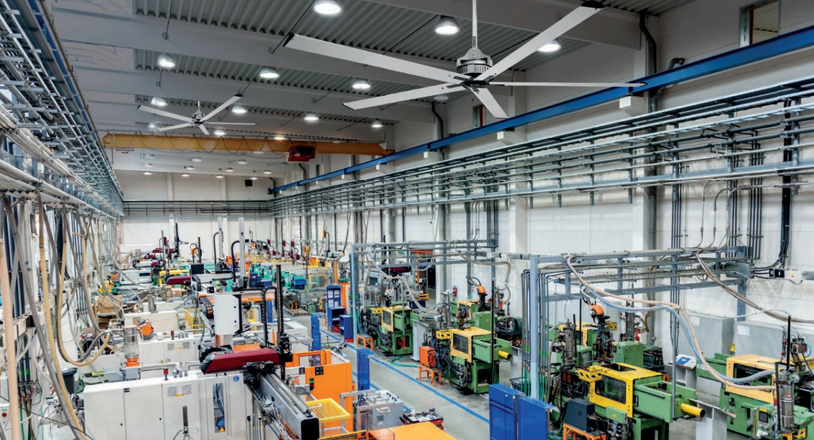 Salle industrielle avec machines-outils, ateliers et systèmes de ventilation suspendus; ambiance dense et équipée. Entretien essentiel pour entretenir son déstratificateur d'air.